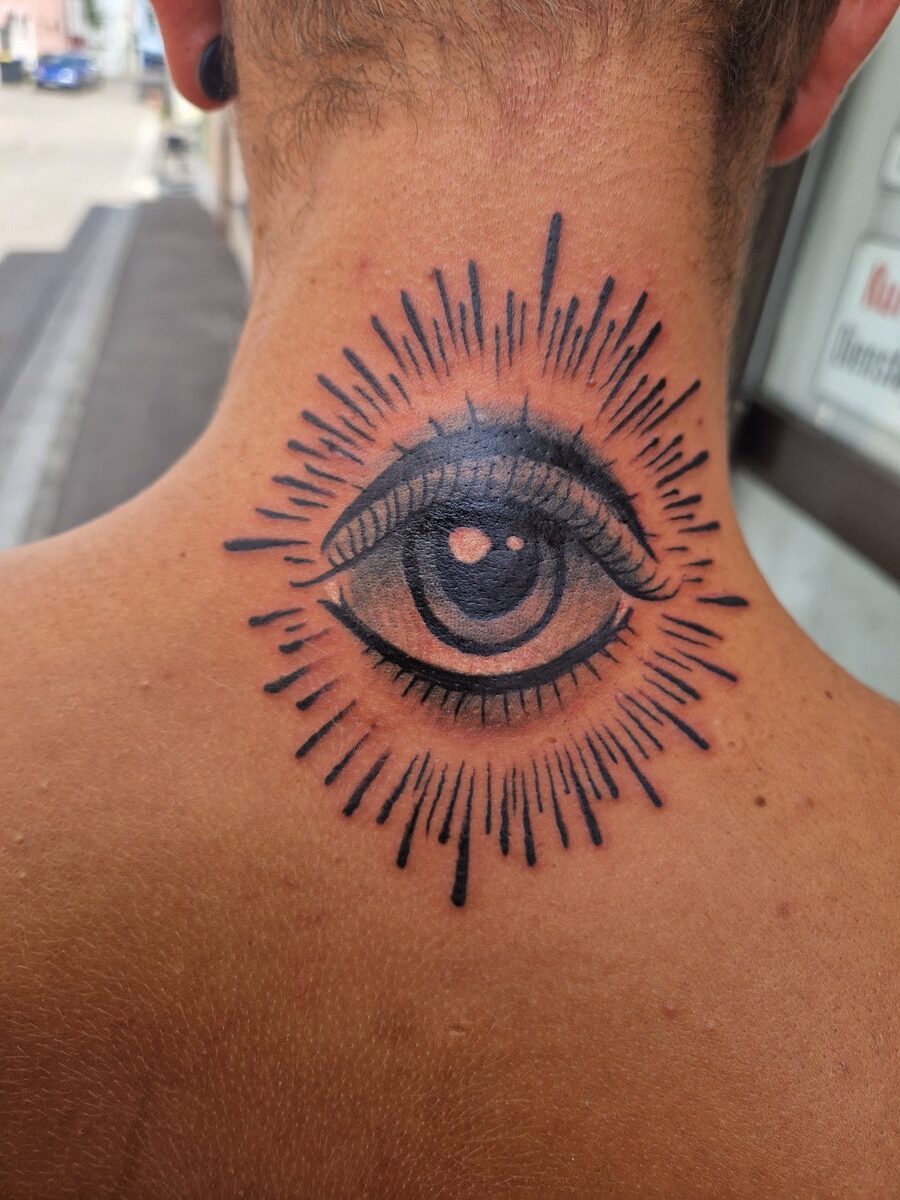Tattoo eines Auges auf dem Nacken, detailliert und schwarz auf heller Haut.