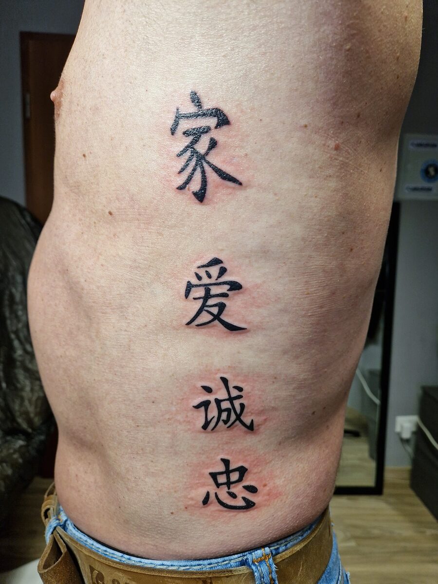 Mittlere Körperseite mit chinesischen Schriftzeichen-Tätowierungen, Haut ist hell.