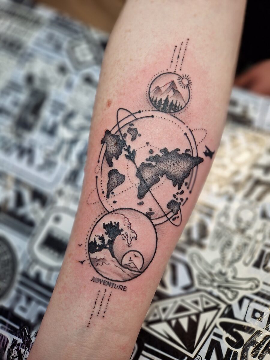 Tattoo auf Unterarm: Weltkarte, Berge, Wellen, Abenteuer; schwarz, geometrische Muster.